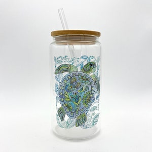 May include: A glass reusable water bottle with a bamboo lid and a straw. The bottle features a colorful, detailed illustration of a sea turtle with a blue, green, and purple shell.
