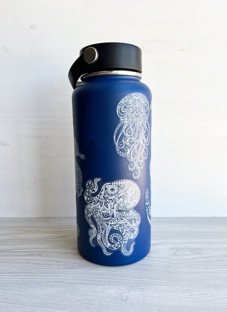 May include: A blue reusable water bottle featuring white octopus and jellyfish designs. The designs are intricate and detailed, resembling a mandala.