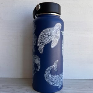 May include: A blue reusable water bottle with white, intricate designs of sea creatures, including a turtle, a whale, and a manatee.