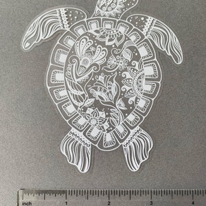 May include: White vinyl sticker of a detailed turtle with a floral mandala design. The turtle is approximately 3 inches wide.