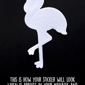 May include: White flamingo sticker with intricate etched details, set against a black background. The sticker's design features a detailed pattern. Text at the bottom reads: "THIS IS HOW YOUR STICKER WILL LOOK WHEN IT ARRIVES IN YOUR MAILBOX AND BEFORE YOU PEEL OFF THE BACKING."