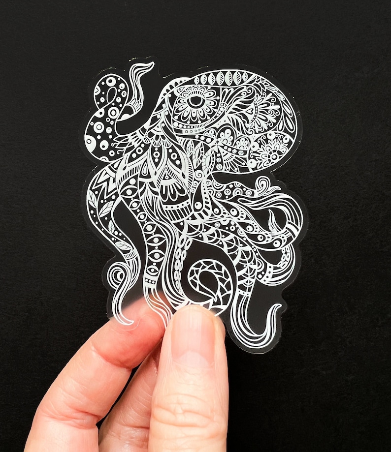 May include: A clear sticker featuring a white outline of an octopus with intricate patterns and designs. The octopus has eight tentacles and is facing to the right.