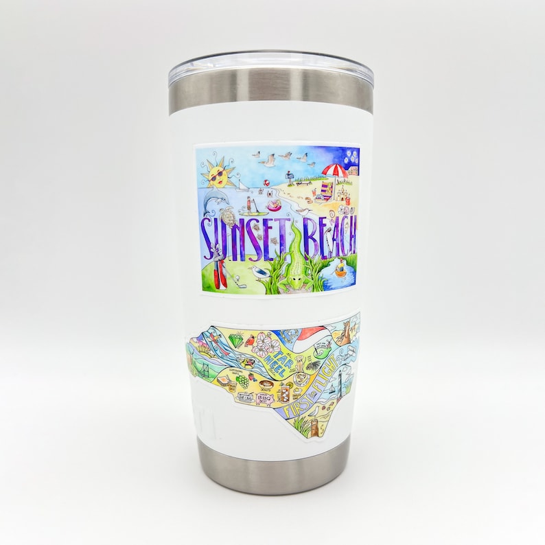 May include: A white insulated tumbler with a silver rim and lid. The tumbler features two colorful stickers. The top sticker says "Sunset Beach" with a beach scene. The bottom sticker is a map of the area.