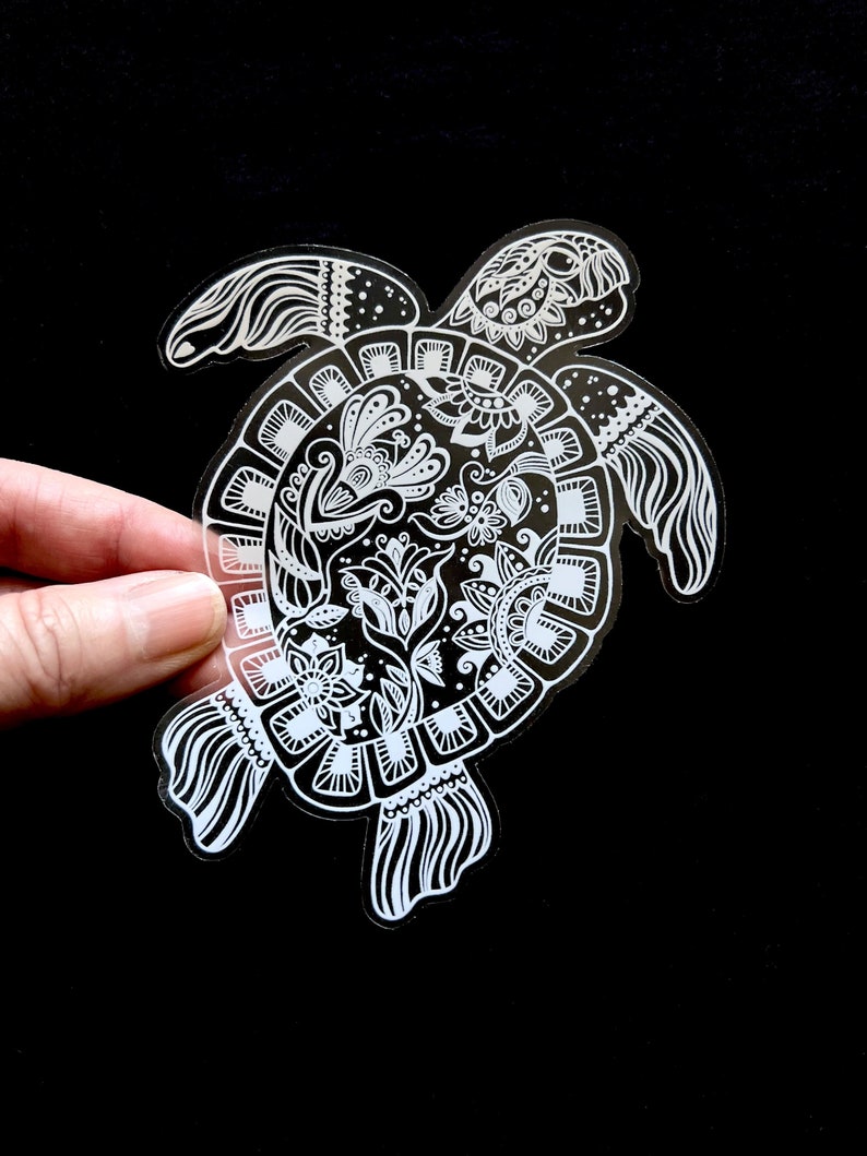 May include: White vinyl sticker of a detailed mandala-style turtle with intricate floral designs. The turtle is facing right and has a long, flowing tail.
