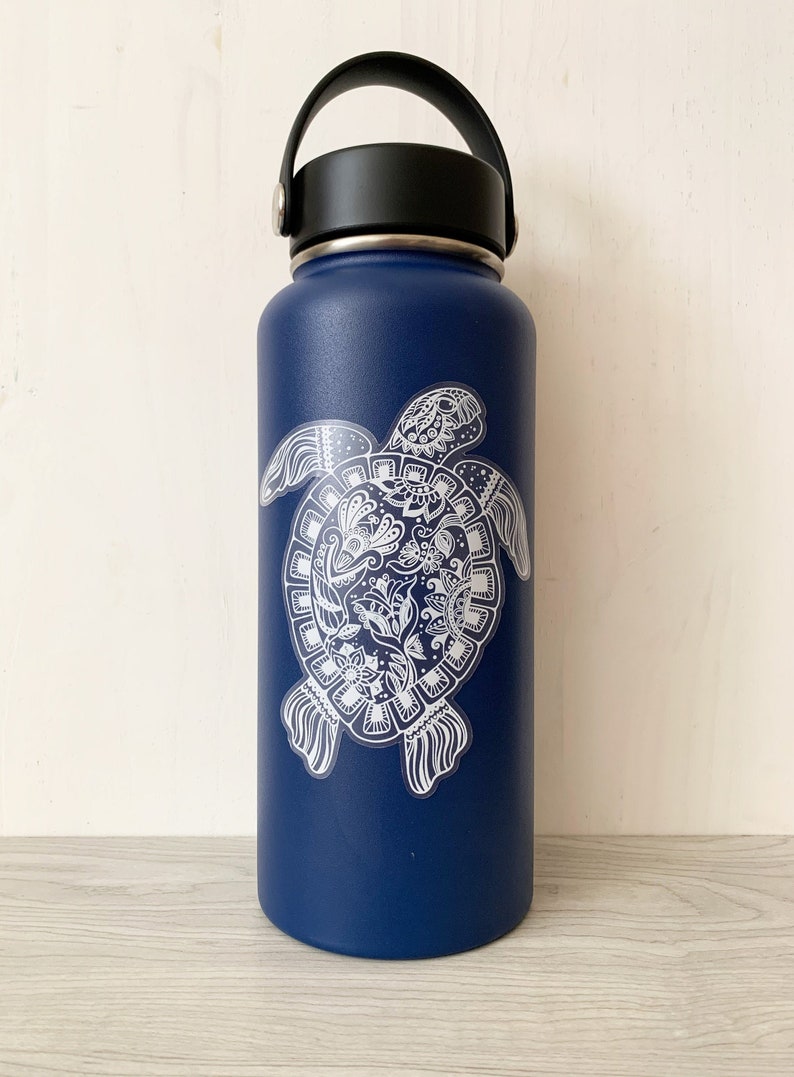 May include: A blue stainless steel water bottle with a white sticker of a detailed mandala-style turtle design.