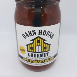 May include: A glass jar of Barn House Gourmet Mild Ripe Tomato Relish, made with all natural vegetables. The jar has a gold lid and a black and yellow label with a barn illustration. The label reads "Barn House Gourmet All Natural Vegetables Ripe Tomato Relish Amish Kitchen Net Wt. 16 oz. KY Made."
