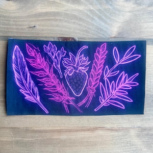May include: A rectangular black fabric patch featuring a neon pink line art illustration. The design displays a central strawberry surrounded by various botanical elements, including a large feather, fern-like fronds, and leafy sprigs.