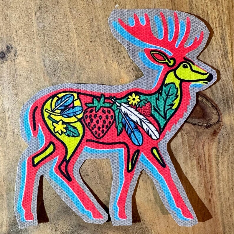Op de afbeelding: Een rood hert silhouet met een blauwe omtrek, versierd met kleurrijke veren, aardbeien en bloemen. Het hert staat op een grijze achtergrond.