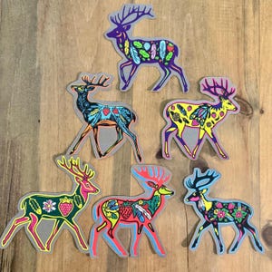 Op de afbeelding: Zes kleurrijke herten stickers met ingewikkelde patronen van veren, bladeren en aardbeien. De herten staan in verschillende poses en hebben verschillende gekleurde lichamen, waaronder paars, blauw, geel en rood.