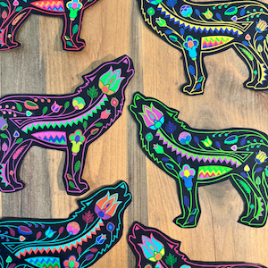 May include: Six colorful wolf silhouettes with intricate floral and geometric patterns. The wolves are howling and have a black background.