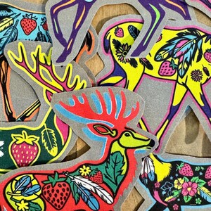 Op de afbeelding: Een verzameling kleurrijke strijkpatches met verschillende dierenontwerpen. De patches bevatten een hert, een eland en een vogel met veren. De patches zijn allemaal felgekleurd en hebben een speelse, volkskunststijl.