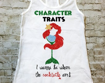 Op de afbeelding: Een wit tanktop met de tekst "Character Traits" in groen en zwart, een rood glitter-zeemeermin-silhouet dat een martini-glas vasthoudt, en de tekst "I wanna be where the cocktails are!"
