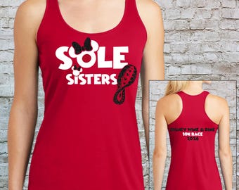 May include: Red racerback tank top with the words "Sole Sisters" in white, a black bow, and a black shoe print design. The back of the tank top has the text "Disney Wine & Dine 10K Race 2016" in black.