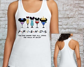 Op de afbeelding: Witte tanktop met een afbeelding met het woord "FRIENDS" in de stijl van het tv-showlogo, met cocktailglazen en Mickey Mouse-oren. De tekst "The one where they all drink too much at EPCOT" staat eronder.