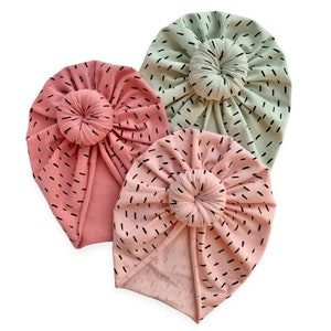 May include: Three fabric headbands in pink and green with a black abstract pattern. The headbands have a knotted design on top.