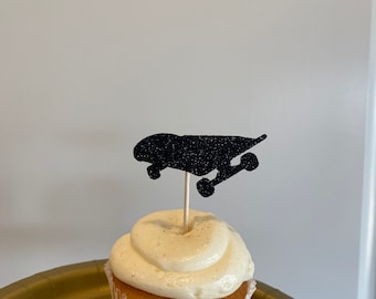 Op de afbeelding: Een cupcake met vanillefrosting bedekt met een zwarte glitter skateboard cupcake topper.