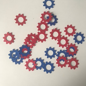 May include: A collection of red and blue paper gears scattered on a white surface.