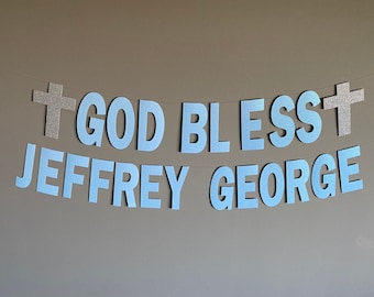 Puede incluir: Una pancarta azul y plateada con el texto "God Bless Jeffrey George" y dos cruces plateadas.
