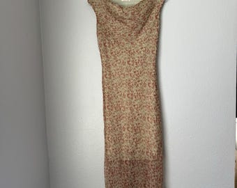 May include: A beige floral print dress with a cowl neckline and cap sleeves. The dress features a pattern of small red flowers and a slightly asymmetrical hemline. The dress is hanging on a white hanger.