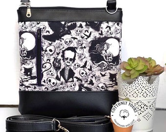 May include: Black and white crossbody bag with a gothic-inspired print featuring skulls, ravens, and a woman with long hair. The bag has a black strap and a zipper closure. The bag is made by Cottonly Yours and says "Handmade with Love".