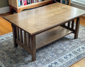 May include: A dark brown wooden coffee table with a lower shelf. The table has a rectangular top and a simple, minimalist design.