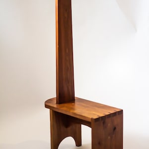 May include: A wooden step stool with a tall back and a handle at the top. The stool is made of solid wood and has a natural finish.