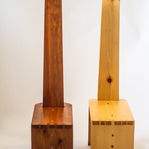 May include: Two wooden step stools with a handle on the back. The stool on the left is a darker brown colour, while the stool on the right is a lighter natural wood colour.