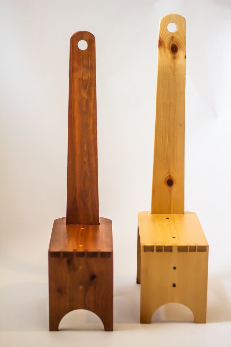 May include: Two wooden step stools with a handle on the back. The stool on the left is a darker brown colour, while the stool on the right is a lighter natural wood colour.