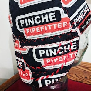 Può includere: Cappello da saldatura nero e rosso con il testo "Pinche Pipefitter" ripetuto sul tessuto. Il cappello è realizzato in un materiale resistente e ha una vestibilità comoda.