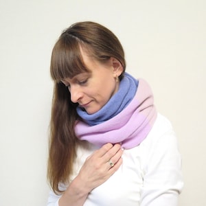 May include: A woman wearing a purple and blue infinity scarf. The scarf is made of a soft, knitted fabric and has a gradient colour design.