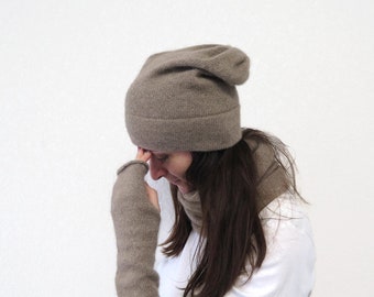 May include: A brown slouchy beanie with a fold-over brim. The beanie is made of a soft, knitted fabric.