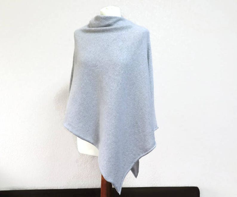 May include: A light gray knitted poncho with a triangular shape.