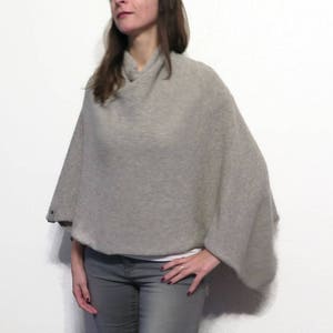 May include: A gray knitted poncho with a cowl neck and long sleeves. The poncho is made of a soft, lightweight fabric and is perfect for layering.