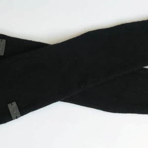 May include: A pair of black arm warmers with a gray logo on each. The arm warmers are made of a soft, stretchy fabric.