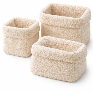 Pode incluir: Conjunto de três cestos de arrumação retangulares creme. Cada cesto tem um exterior macio, texturizado e felpudo. Os cestos variam em tamanho, sendo o maior atrás e o menor à frente. Ideal para organizar itens em casa ou no escritório.