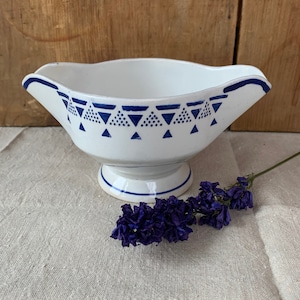 Könnte beinhalten: Eine weiße, gravierte Sauciere mit einem blauen und weißen geometrischen Muster. Die Sauciere hat einen Fuß und einen Ausgießer.