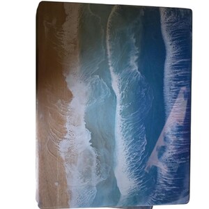 May include: A rectangular wooden serving tray with a resin ocean wave design. The tray features a sandy beach on the left, transitioning to foamy white waves and deep blue ocean on the right. The resin gives a glossy finish.
