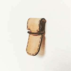 May include: A light brown leather strap with a stitched edge and a metal buckle. The strap is attached to a wall.