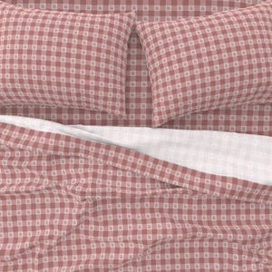 May include: Bedding set with a pink and white gingham design. The set includes two pillowcases and a fitted sheet. The sheets and pillowcases are made of a soft, comfortable material. The overall theme is a classic, country style.