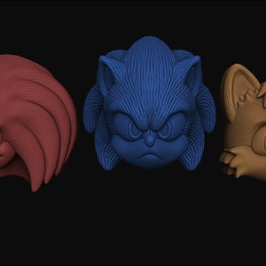 May include: Three 3D printed character heads from the Sonic the Hedgehog video game series. The heads are of Sonic, Knuckles, and Tails. Sonic is blue with a serious expression, Knuckles is red with a smirk, and Tails is orange with a surprised expression.