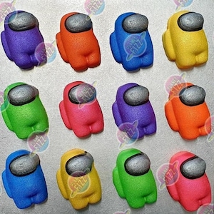May include: Twelve colorful bath bombs shaped like the characters from the video game Among Us. The bath bombs are in various colors, including purple, orange, green, pink, blue, and yellow.