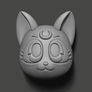 May include: A grey 3D printed model of a cat's face with large eyes and a crescent moon on its forehead.