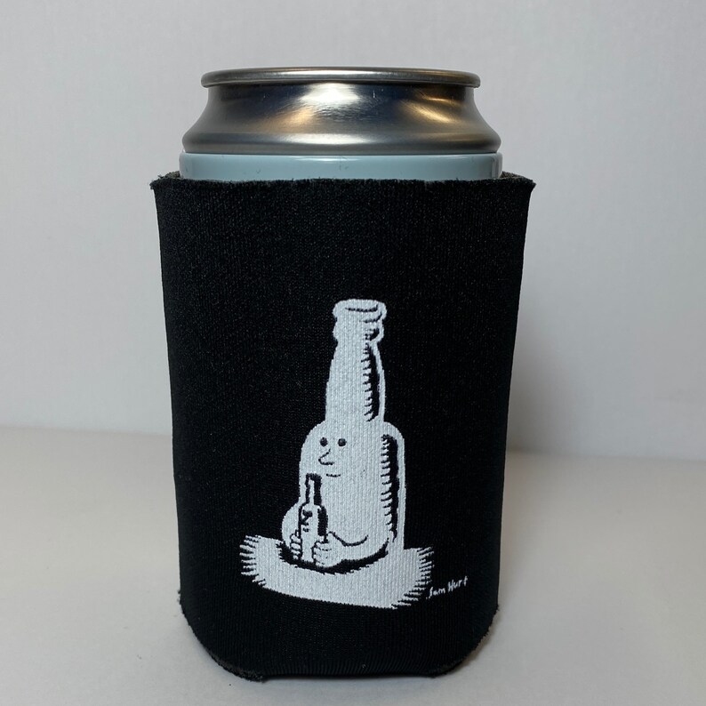 Peut inclure: Glaci&egrave;re en n&eacute;opr&egrave;ne noire avec une illustration blanche d'un personnage en bouteille tenant une plus petite bouteille. L'illustration est sign&eacute;e "Sam Hurt".
