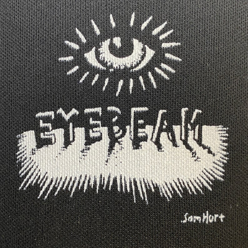 Peut inclure: Illustration en noir et blanc d'un &oelig;il avec un motif de soleil &eacute;clatant au-dessus du mot "EYEBEAM" dans une police de caract&egrave;res stylis&eacute;e. La signature de l'artiste "Sam Hurt" se trouve dans le coin inf&eacute;rieur droit.
