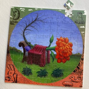 May include: A jigsaw puzzle depicting a surreal scene with a large red flower growing from a sofa, a bare tree, and a green lawn. The puzzle is nearly complete, with only a few pieces missing.