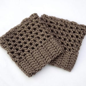 May include: A pair of brown crocheted boot cuffs with gold glitter thread. The cuffs are made with a simple stitch pattern and have a slightly textured look.