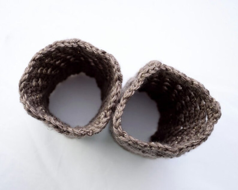 May include: Two brown crocheted wrist warmers with a sparkly thread woven into the fabric.