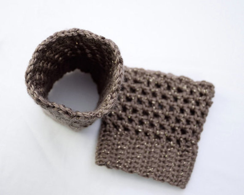 May include: Two brown crocheted pieces with a sparkly thread. One piece is a tube and the other is a square.