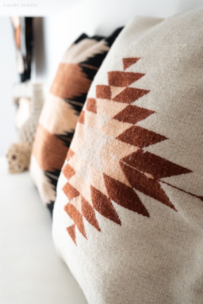 Puede incluir: Dos almohadas con patrones geom&eacute;tricos. La almohada en primer plano es beige con un dise&ntilde;o geom&eacute;trico marr&oacute;n y melocot&oacute;n. La almohada en el fondo es beige con un dise&ntilde;o geom&eacute;trico negro, marr&oacute;n y melocot&oacute;n.