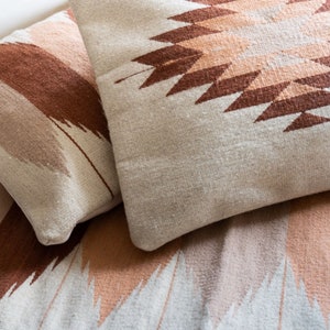 Puede incluir: Dos almohadas decorativas con patrones geom&eacute;tricos en tonos marrones, rosas y blancos. Las almohadas est&aacute;n hechas de un tejido suave y tejido.